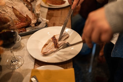 Persona Sosteniendo Tenedor Y Cuchillo De Plata Sobre Placa De Cerámica Blanca