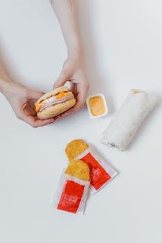 Delicious breakfast featuring a burrito, hash brown patties, and a sandwich on a white background.