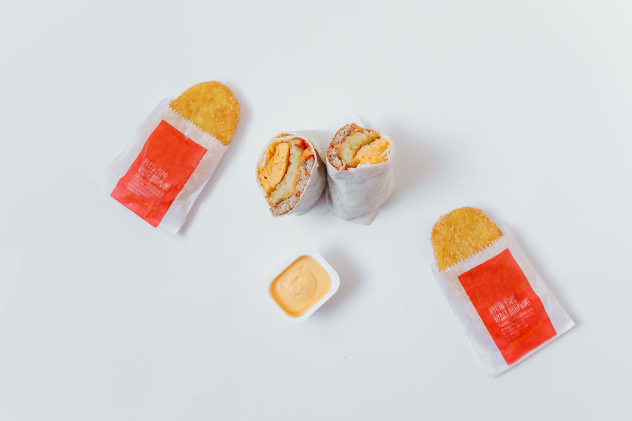 flat lay of breakfast burrito and hash browns with sauce on white back