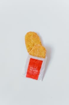 Flatlay of crispy hash browns in packaging on a plain white background, perfect for breakfast themes.