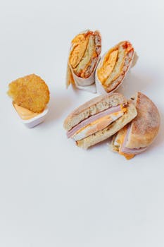 Tasty breakfast burrito and sandwich with hash brown on a white background.