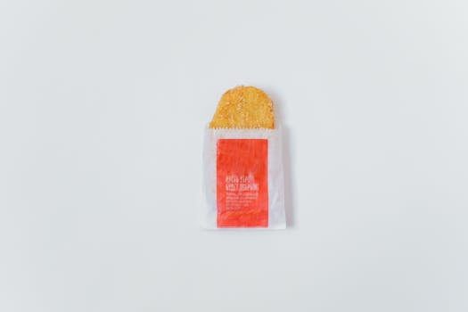Top view of a crispy hash brown partially wrapped in fast food paper.