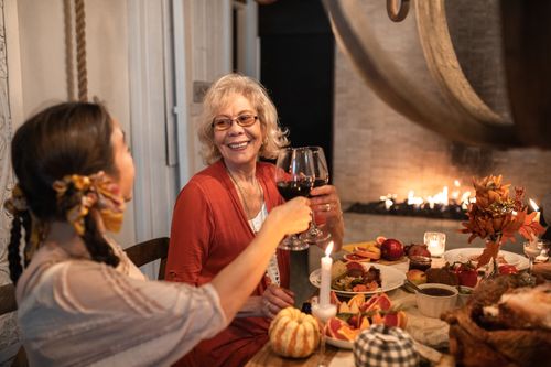 Free Two women toasting with red wine during a warm Thanksgiving dinner indoors. Stock Photo