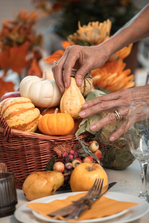 Free A decorative autumn table setting featuring a basket of gourds and fruits for a festive holiday theme. Stock Photo