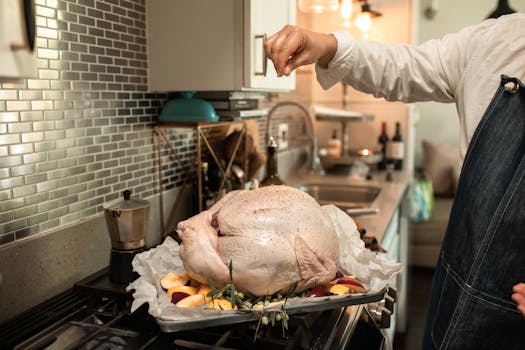 A person seasons an uncooked turkey in a cozy kitchen setting, ready for Thanksgiving dinner.