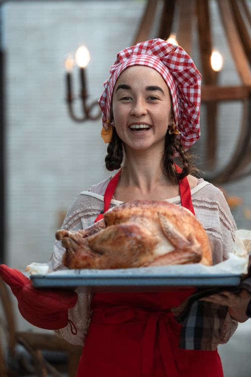 Free A woman joyfully presents a perfectly roasted turkey for a festive Thanksgiving celebration. Stock Photo