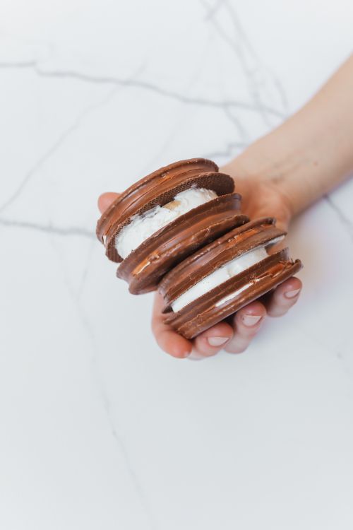 Free Close-up of hand holding chocolate macarons with creamy filling. Stock Photo