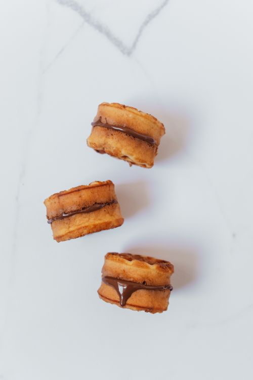 Free Three chocolate-filled cookie sandwiches on a clean white background, enticing and sweet. Stock Photo
