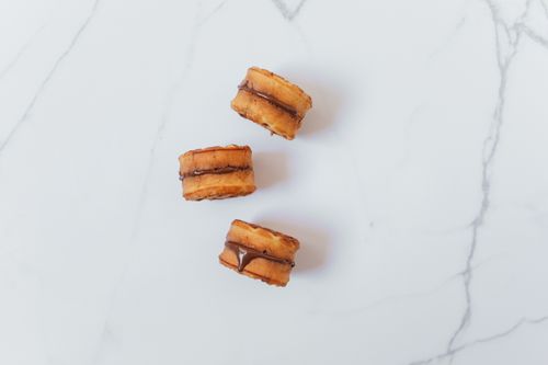 Free Top view of three chocolate-filled pastry bites on a marble surface, perfect snack idea. Stock Photo