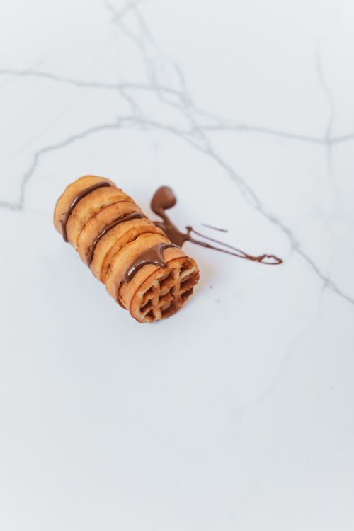Free A tempting close-up of a rolled pastry topped with chocolate glaze on a marble surface. Stock Photo