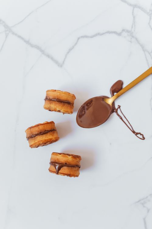 Free Top view of chocolate dipped sandwich cookies with a spoon on a marble surface. Stock Photo