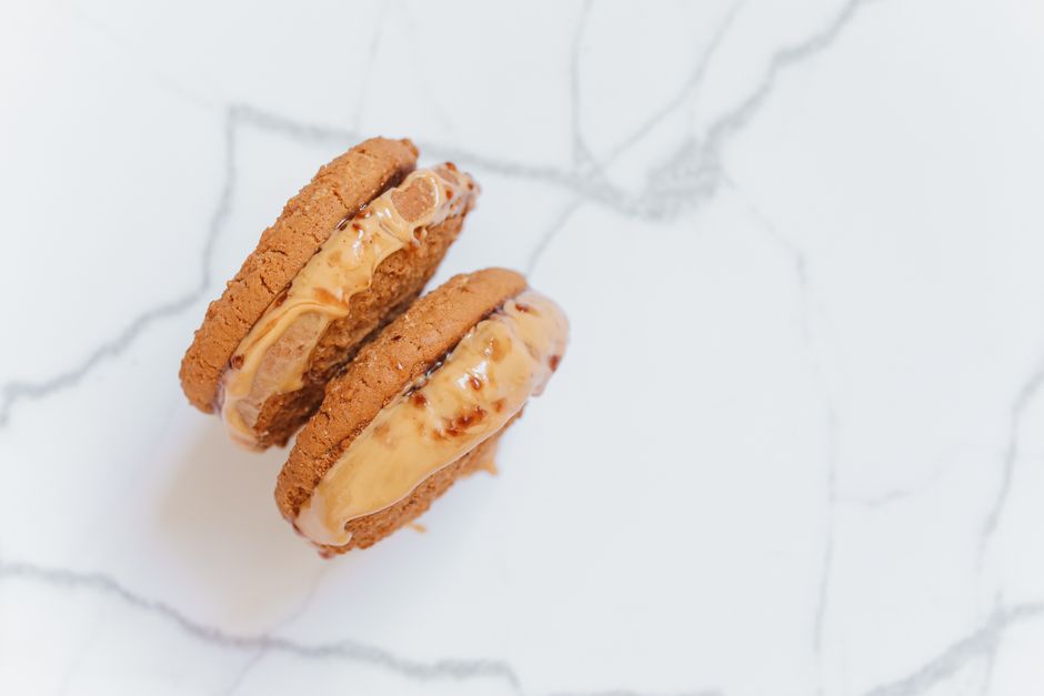 A stack of peanut-shaped Nutter Butter sandwich cookies next to a bowl of crushed cookie crumbs used for a pie crust.