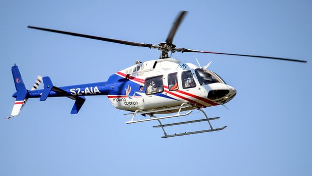 A helicopter soaring through the clear blue sky with passengers visible, showcasing aviation technology.