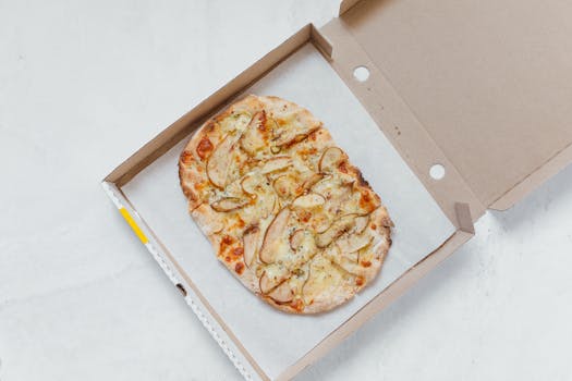 A delicious gourmet pizza with toppings in an open box, shot from above for a tempting view.