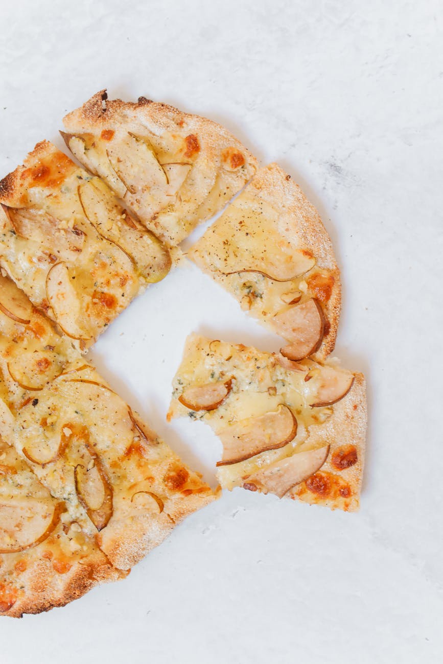 Flatlay of sliced pizza with pears and cheese for an Italian culinary delight.