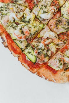 A delectable Italian seafood pizza topped with shrimp and zucchini slices, perfect for gourmet dining.