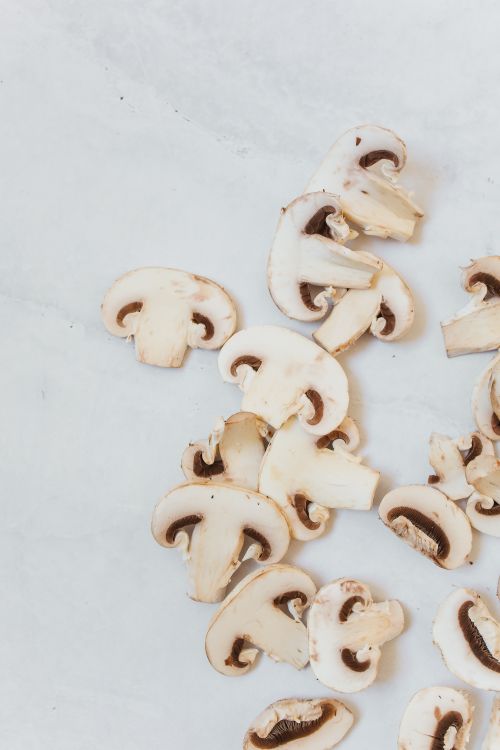 Free Close-up of fresh sliced button mushrooms on a white background, perfect for cooking or food styling. Stock Photo