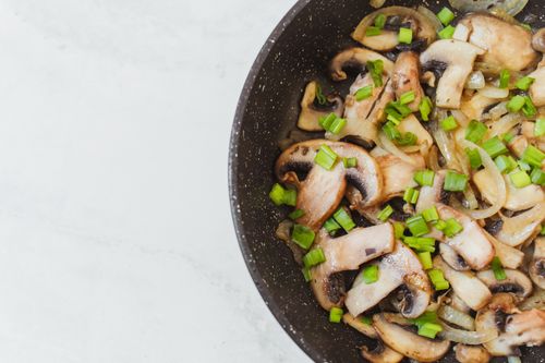 Free Top-down view of sautéed mushrooms and spring onions in a frying pan. Stock Photo