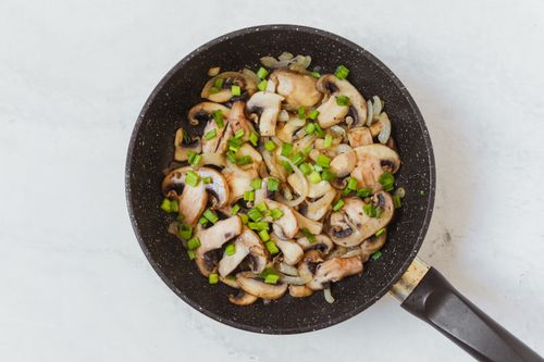 Free Top view of sautéed mushrooms and spring onions cooking in a frying pan. Stock Photo