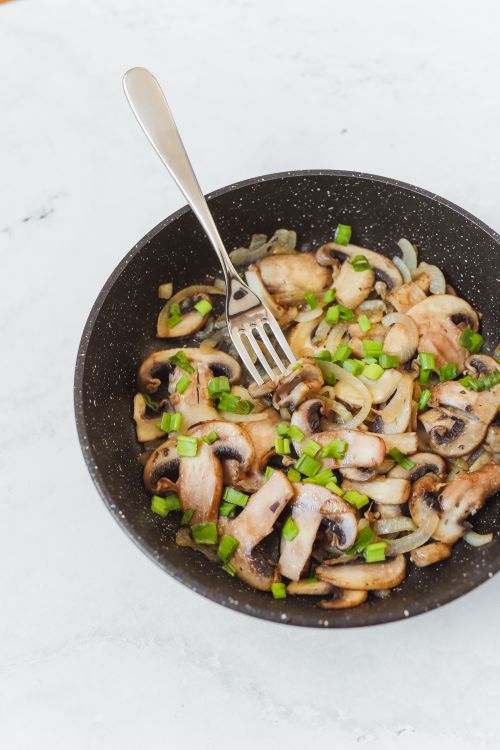 Free Delicious stir-fried mushrooms and onions garnished with green onions in a frying pan. Stock Photo