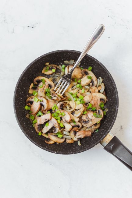 Sautéed diced onions in a black skillet with visible caramelization`