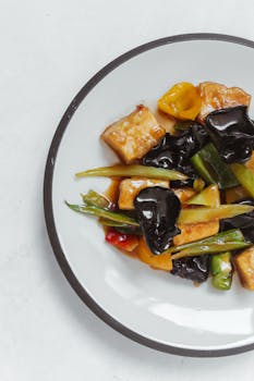 Flat lay of stir-fried tofu with mixed vegetables on a plate. Perfect for Asian cuisine lovers.