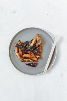 Delicious Asian-style eggplant dish on a plate with chopsticks, perfect for food enthusiasts.