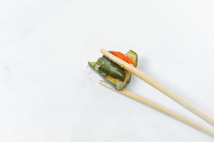 Close Up Photography Of Pickled Cucumber On Chopsticks