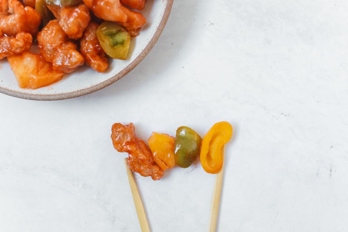 Sweet and sour chicken close-up with chopsticks over rice