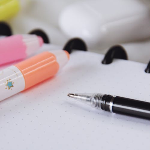 Free High angle of markers placed with pen on notepad near case for wireless earbuds Stock Photo
