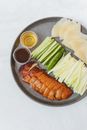 盘子上放着北京烤鸭片、黄瓜、煎饼和酱汁，这是一道经典的亚洲美食