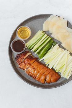 盘子上放着北京烤鸭片、黄瓜、煎饼和酱汁，这是一道经典的亚洲美食