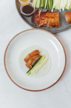 传统北京烤鸭的特写镜头，配上青葱和酱汁，展现了美食的魅力