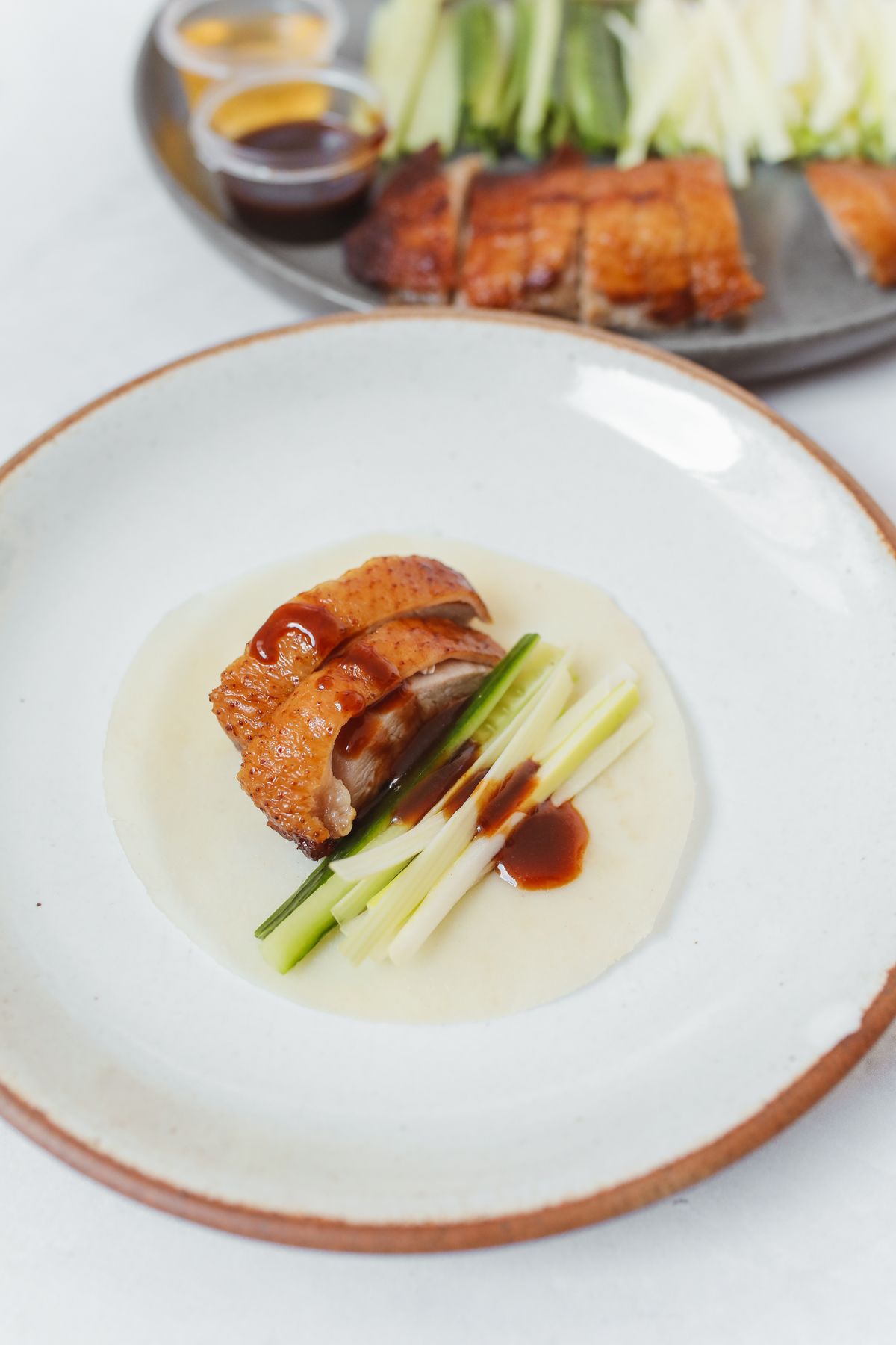 Overhead view of a Peking duck serving platter with cucumber, scallions, hoisin sauce and Mandarin pancakes ready to be assembled into wraps.