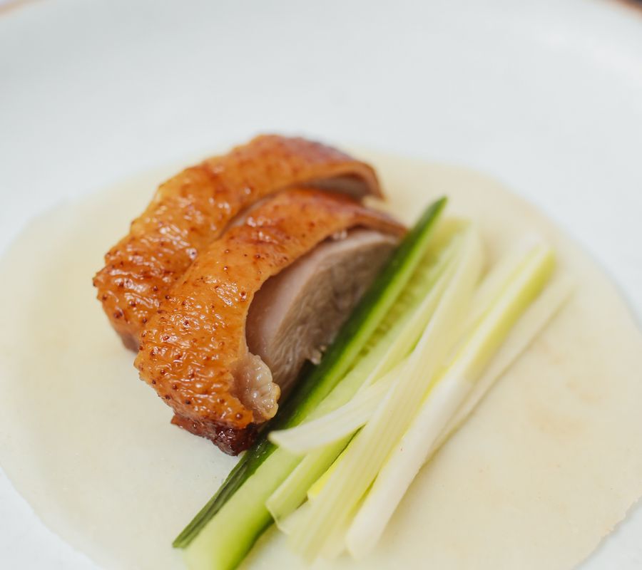 Delicious Peking duck served with cucumber and scallions on a thin pancake.