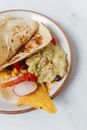 盘中装有鳄梨酱、豆类、玉米和新鲜蔬菜的美味墨西哥玉米卷