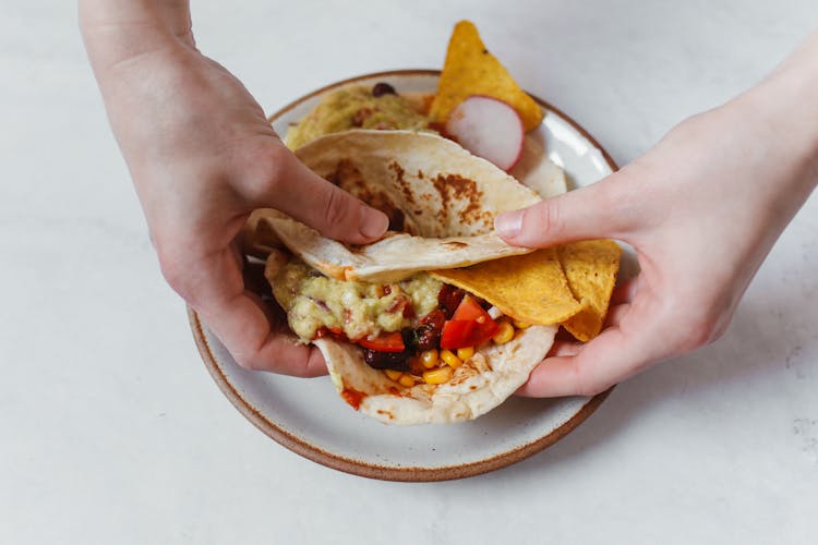 Person Holding A Taco With Chips