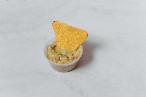 Free A close-up image of nachos and guacamole in a mini container, perfect snack. Stock Photo