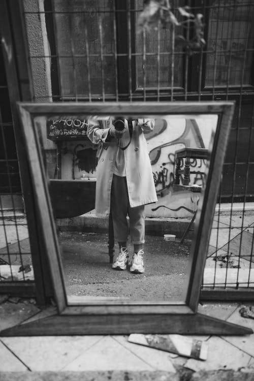 Free Grayscale Photo of Person Standing in Front of a Mirror Holding Camera Stock Photo