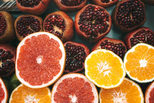 Close-up view of colorful sliced citrus fruits and pomegranates showcasing freshness and nutrition.