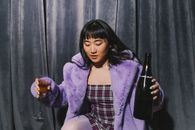一位身穿紫色毛皮大衣的亚洲妇女，用葡萄酒庆祝新年