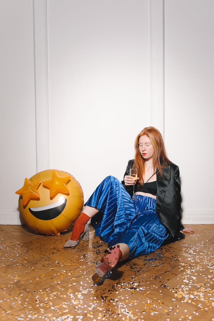 A Woman Holding Glass Of Wine While Sitting On The Floor