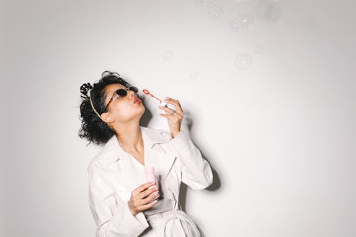 Woman in White Coat Blowing Bubbles