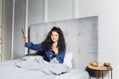 Free Woman with Curly Hair Lying in Bed Stock Photo