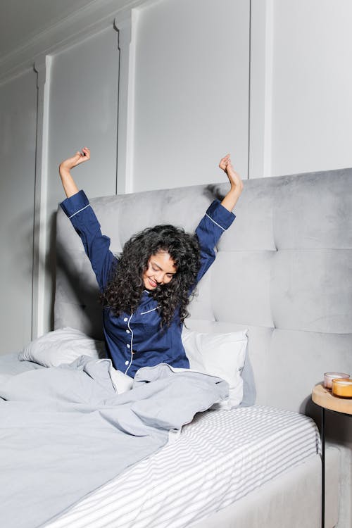 Free Woman with Curly Hair Sitting on Bed  Stock Photo