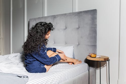 Free Woman with Curly Hair Sitting on Bed  Stock Photo