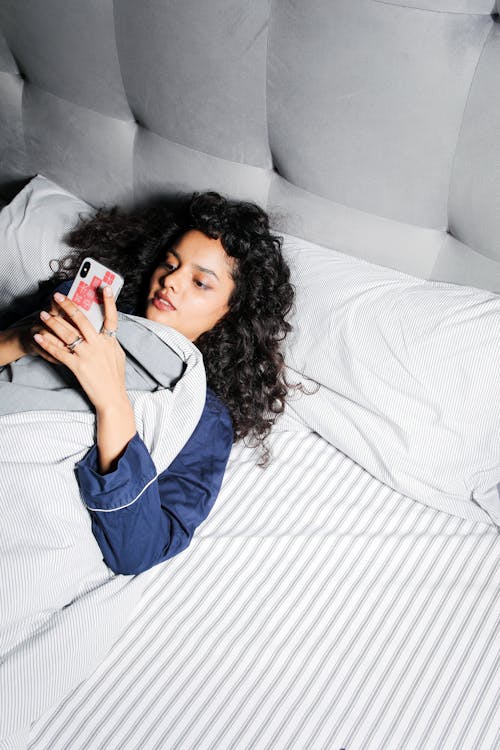 Free Woman in Blue Sleepwear Lying on Bed Stock Photo