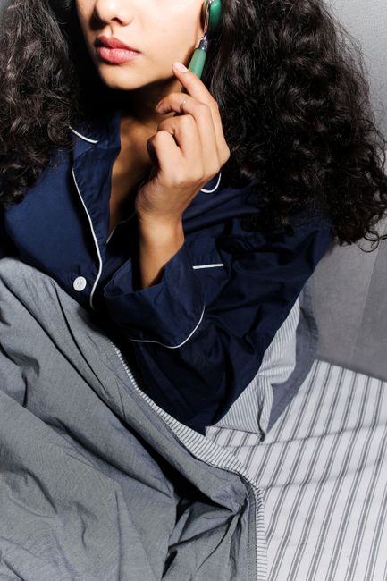 Close-up of a woman using a jade roller in bed, focusing on skincare and relaxation.