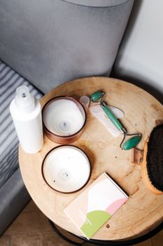 Top view of skincare items and candles on a wooden table.
