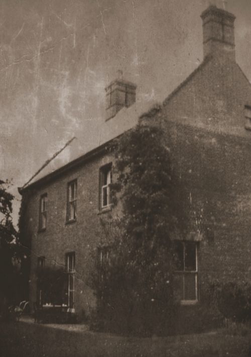 Free A vintage photograph of an ivy-covered brick house with prominent chimneys. Stock Photo